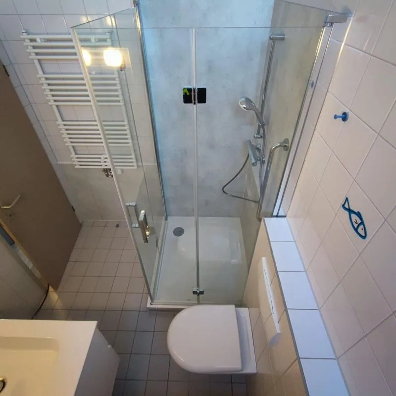 Neue Eckdusche mit fugenlosen Wandpaneelen in einem bestehenden gefliesten Bad